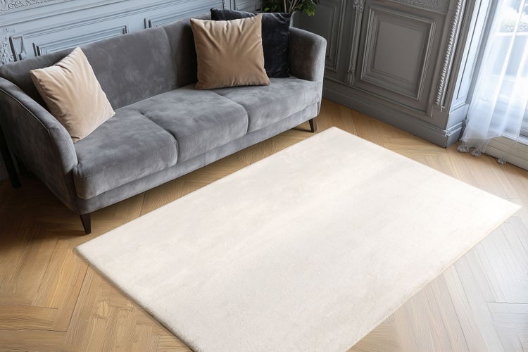Obdélníkový jednobarevný koberec do obývacího pokoje na dřevěné podlaze před pohovkou v elegantně zařízeném interiéru.