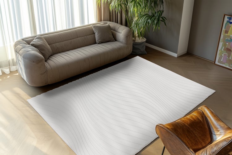 Moderní obdélníkový koberec s vlnitým vzorem leží v elegantním obývacím pokoji před pohovkou a křeslem na parketové podlaze.