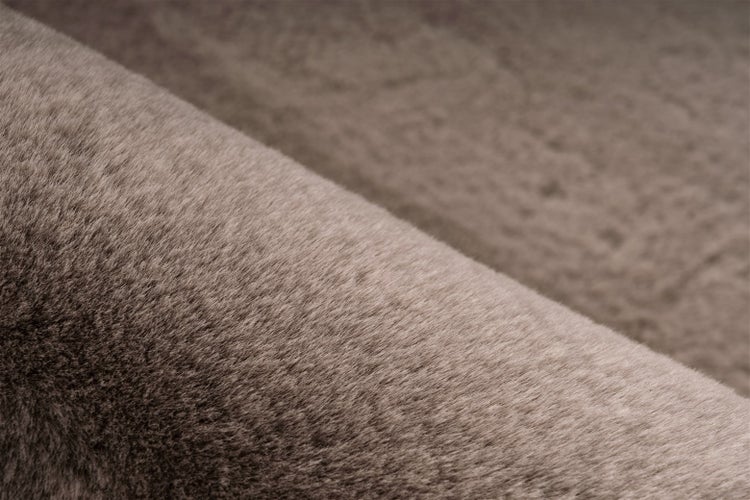 Detailní záběr na měkký, hnědý koberec z umělé kožešiny s hustými, jemnými vlákny.