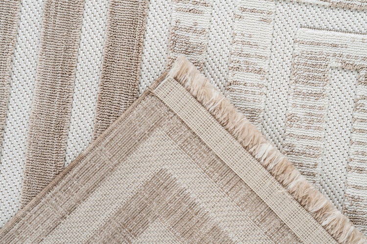 Detailní záběr na tkaný koberec s geometrickým vzorem, zobrazující lícovou i rubovou stranu a okraj s třásněmi.