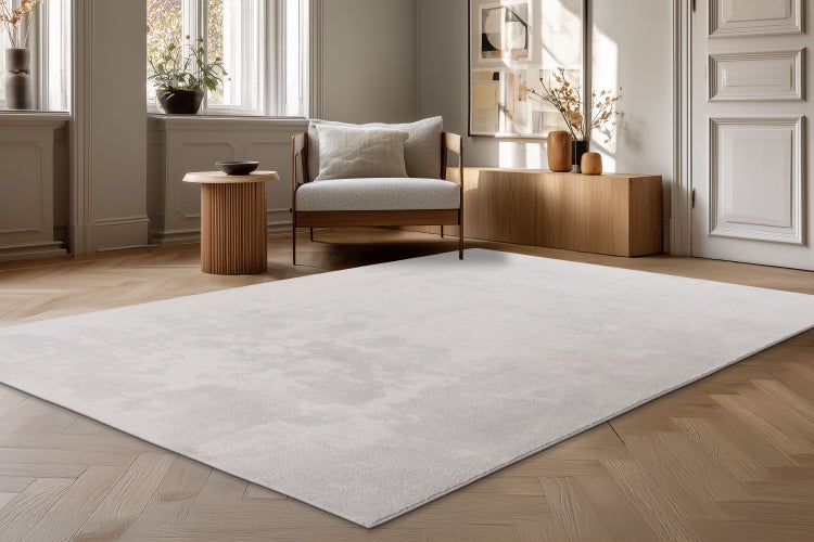 Světlý moderní koberec do obývacího pokoje na parketové podlaze v elegantně zařízené místnosti s křeslem a dřevěným nábytkem.