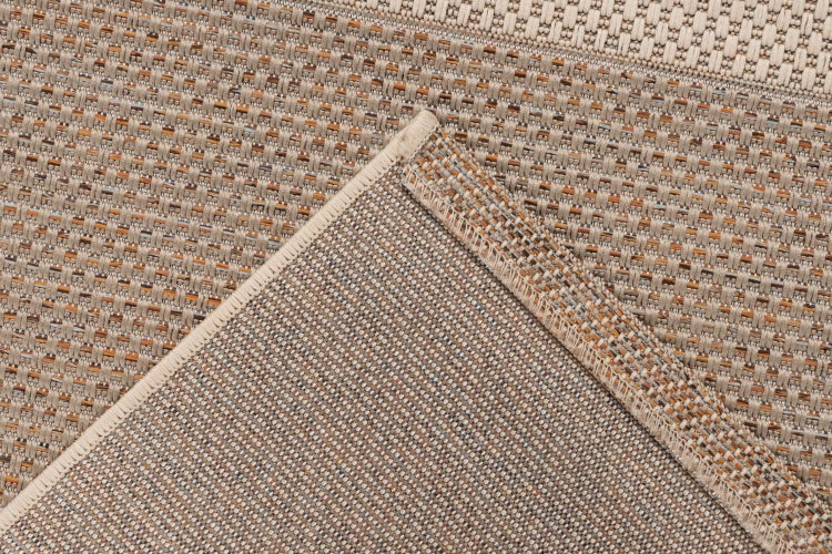 Detailní pohled na koberec s tkanou strukturou a obšitým okrajem