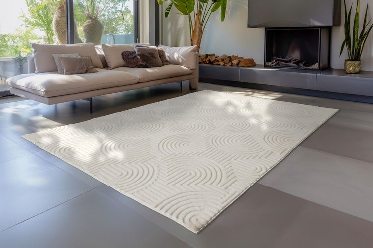 Moderní koberec do obývacího pokoje se strukturovaným vzorem kruhových oblouků na hladké podlaze před pohovkou v prosvětleném elegantním interiéru.