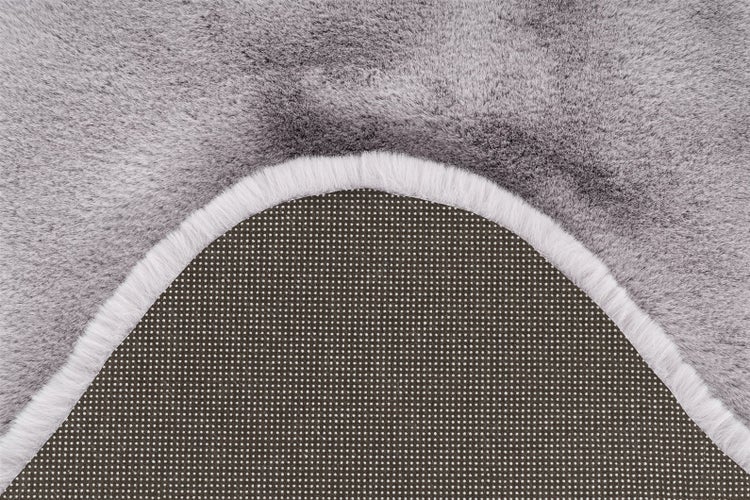 Detailní pohled na šedý koberec z umělé kožešiny s měkkým povrchem a protiskluzovou zadní stranou s nopky.