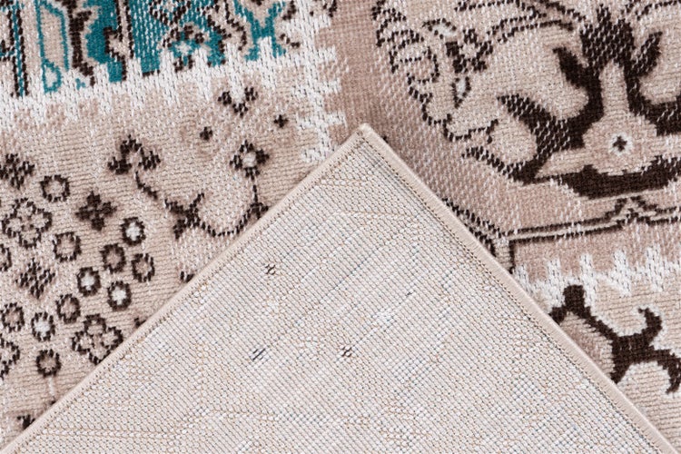 Detail koberce ve vintage stylu s tkaným vzorem a ohrnutým rohem ukazujícím zadní stranu.