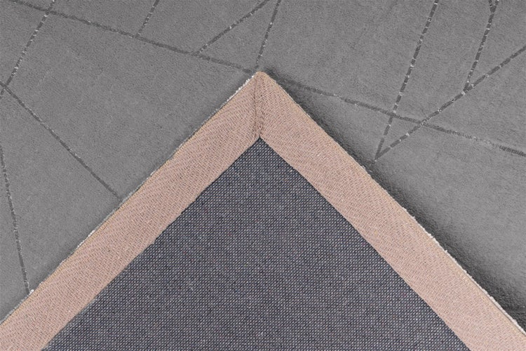 Detailní záběr na roh koberce s geometrickým vzorem a rubovou stranou se zpevněným okrajem.