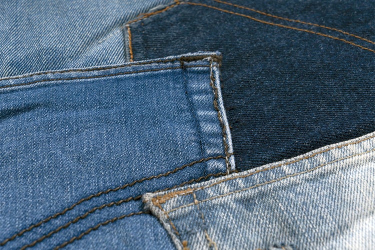 Detailní záběr na různé džínové látky s viditelnými švy a různými texturami pro pracovní oděvy