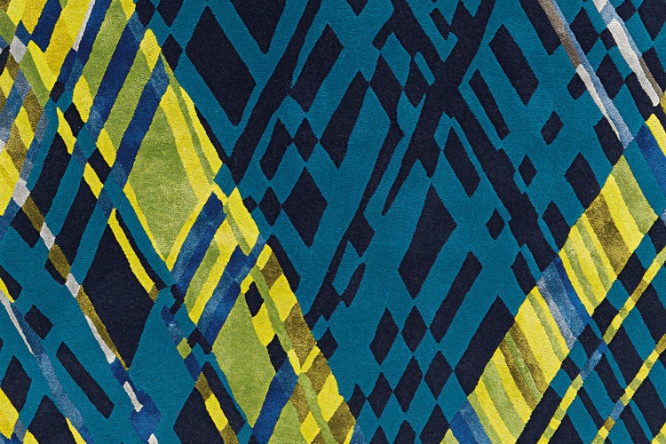 Geometrický vzor koberce s kosočtverci a liniemi v modré a žluté barvě, strukturovaný textilní povrch.