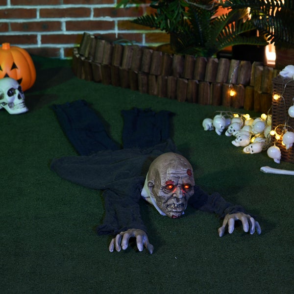 Dekorativní halloweenská scéna s lezoucím zombie, dýní, lebkou a světelným řetězem