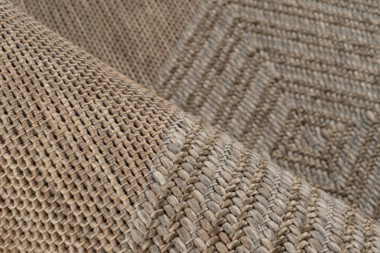Detailní záběr tkaného koberce s geometrickým vzorem kosočtverců.