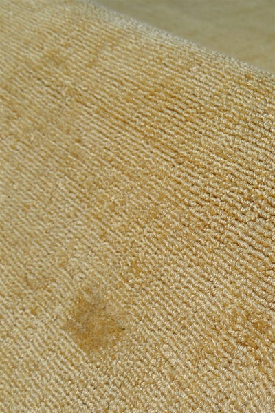 Detailní pohled na béžový koberec se smyčkovou strukturou.