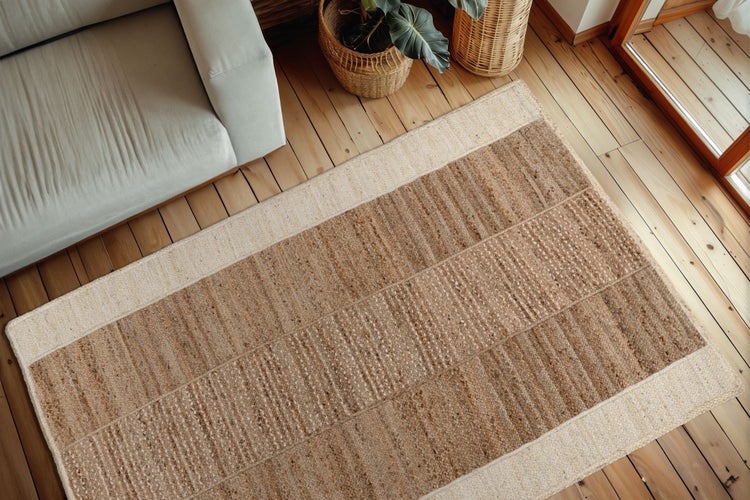 Obdélníkový jutový koberec se strukturovaným tkaným vzhledem a hladkým okrajem na dřevěné podlaze v moderně zařízeném obývacím pokoji.