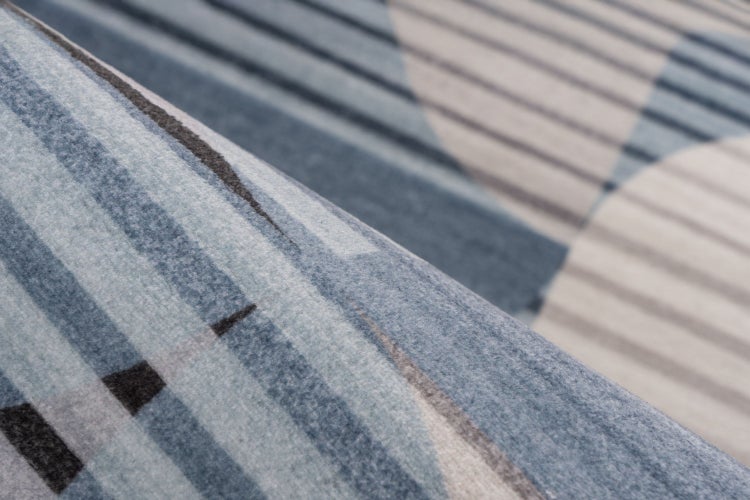 Detail textilní tkaniny se strukturovaným pruhovaným vzorem a organickými tvary pro bytový textil nebo dekorace.