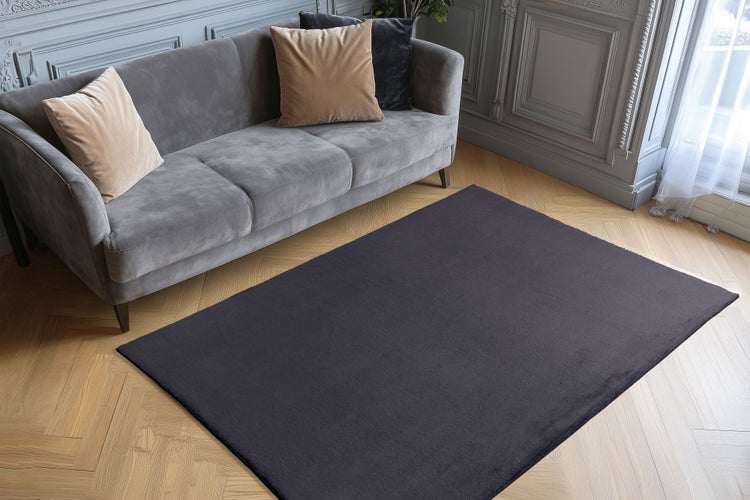 Obdélníkový koberec před pohovkou na parketové podlaze v elegantně zařízeném obývacím pokoji.