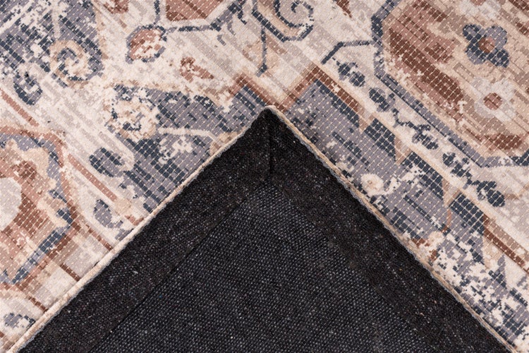 Detailní záběr koberce s vintage vzorem a tmavou strukturovanou zadní stranou viditelnou na přehnutém rohu.