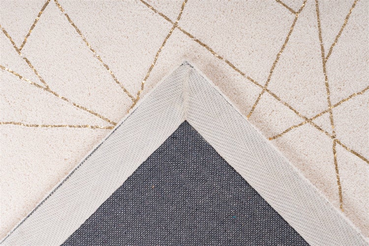 Detailní záběr na koberec s geometrickým vzorem zlatých linií na měkkém vlasu, v rohu je vidět texturovaná textilní zadní strana.
