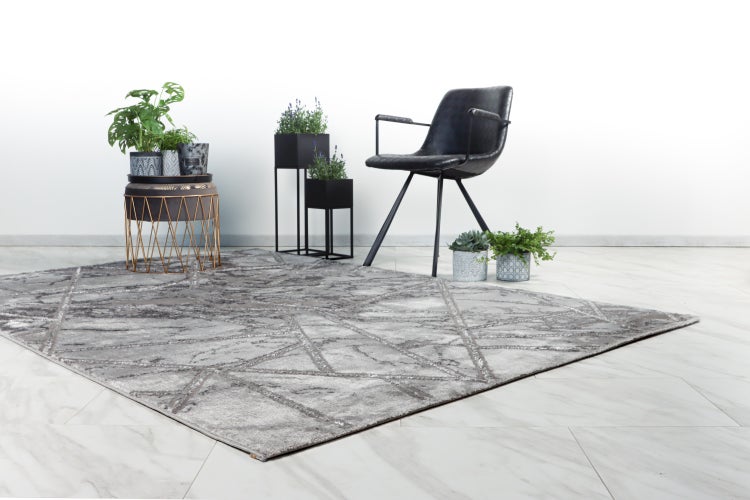 Šedý moderní koberec s geometrickým vzorem ve stylově zařízeném obývacím pokoji s křeslem a rostlinami.