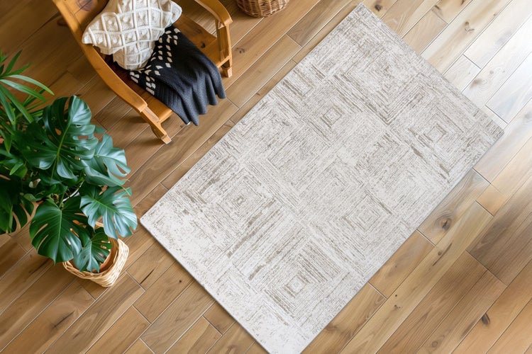 Obývací pokoj s kobercem s geometrickým vzorem na parketové podlaze vedle křesla s dekou a pokojovou rostlinou monstera.