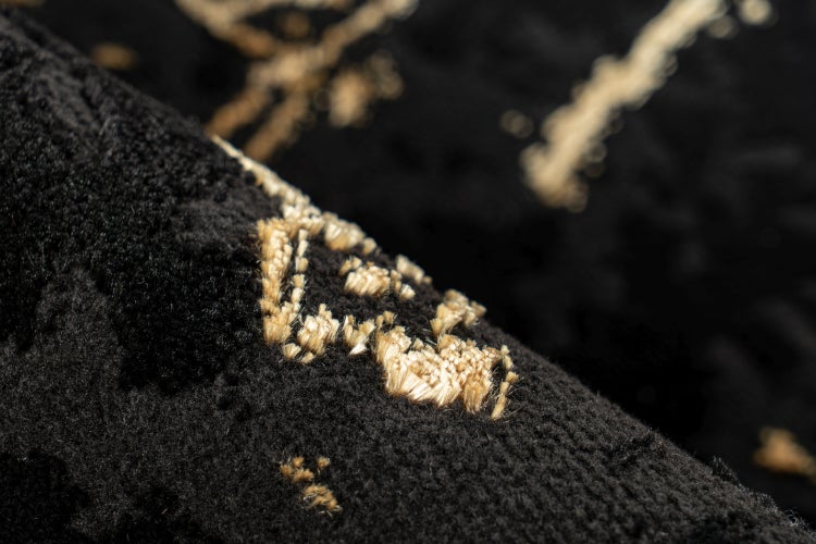 Detailní záběr na huňatý koberec se strukturovaným povrchem a vetkanými vzory.