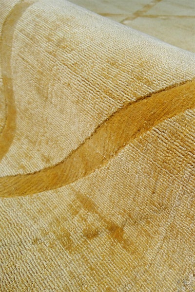 Detailní pohled na béžový koberec s texturovaným povrchem a zakřiveným vzorem.