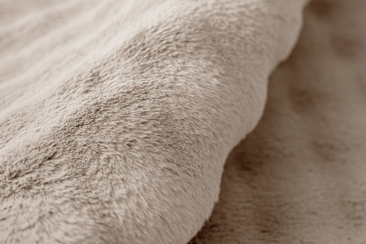 Detailní záběr na měkký koberec z umělé kožešiny s plyšovou texturou.